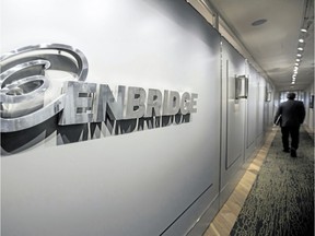 An Enbridge employee walks past signage at the company's head office in Calgary in this file photo.