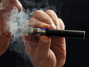 FILE - In this Jan. 17, 2014 file photo, a smoker demonstrates an e-cigarette in Wichita Falls, Texas. Soon, the Food and Drug Administration will propose rules for e-cigarettes. The rules will have big implications for a fast-growing industry and its legions of customers.