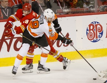Matthew Tkachuk of the Calgary Flames reaches around Claude Giroux of the Philadelphia Flyers during NHL action in Calgary, Alta., on Wednesday, Feb. 15, 2017. Lyle Aspinall/Postmedia Network
