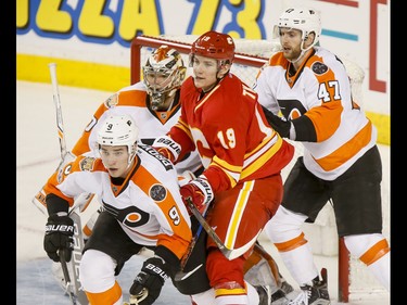 Matthew Tkachuk of the Calgary Flames is sandwiched between Ivan Provorov (L) and Andrew MacDonald of the Philadelphia Flyers in front of goalie Michal Neuvirth during NHL action in Calgary, Alta., on Wednesday, Feb. 15, 2017. Lyle Aspinall/Postmedia Network