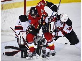 New Jersey Devils' Travis Zajac, right, shoves Calgary Flames' Alex Chiasson, centre, away from goalie Keith Kinkaid during third period NHL hockey action in Calgary, Friday, Jan. 13, 2017.