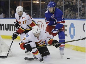 New York Rangers' Oscar Lindberg (24) fights for the puck with Calgary Flames' TJ Brodie (7) and Lance Bouma (17) during the second period of an NHL hockey game Sunday, Feb. 5, 2017, in New York.