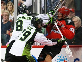 The Calgary Roughnecks' Jon Harnett is checked by the Saskatchewan Rush's Mike Messenger and Nic Bilic during National Lacrosse League action at the Scotiabank Saddledome in Calgary on Saturday February 4, 2017.