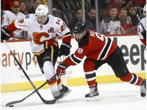Calgary Flames center Sean Monahan (23) and New Jersey Devils left wing Taylor Hall (9) compete for the puck during the first period of an NHL hockey game, Friday, Feb. 3, 2017, in Newark, N.J.