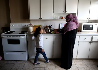 Fatima al-Rajab prepares dinner for her family as her daughter Amani, 7, helps.