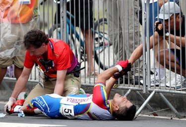 Spectators hold Venezuelan Victor Hugo Marquez Garrido's hands as he is examined by medics. Garrido crashed during the men's road race at the Rio Paralympics in Rio De Janerio, Brazil on Friday September 16, 2016.