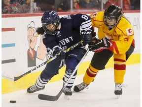 Tianna Ko of the Mount Royal Cougars goes for a puck against Megan Grenon of the Calgary Dinos in the women's game of the Crowchild Classic in Calgary, Alta., on Thursday, Feb. 2, 2017. It was the fifth annual CIS match-up between the University of Calgary and Mount Royal University.