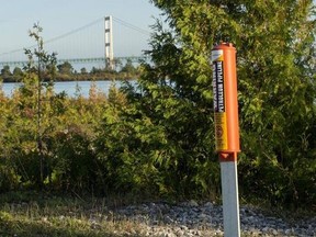 FILE- In this Sept. 23, 2015, file photo, the Mackinac Bridge is visible from a marker near Enbridge Line 5 on the northern shore of the Straits of Mackinac in Michigan. Operators of twin oil pipelines beneath the swirling waterway where Lakes Huron and Michigan converge insisted Monday, March 13, 2017, that they remain structurally sound even though an outer layer of protective covering has worn away in some places, while skeptics said the deterioration is further evidence the lines should be s