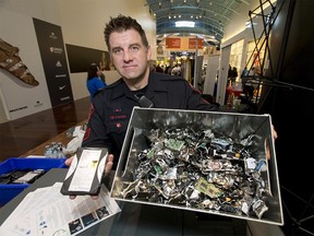 Sgt. Andrew MacLeod of the Calgary Police Service's Cyber Investigations Team holds a hard drive and a box of destroyed electronics at CrossIron Mills north of Calgary, Alta., on Saturday, March 18, 2017. The CPS and a bevy of other agencies were set up at the mall to educate about cyber crime, and to receive/dispose of electronics to be recycled. Lyle Aspinall/Postmedia Network