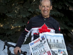 Wallace King holds two Omani newspapers, the Week and the Observer, both featuring stories about him and seven others who cycled across Oman for charity, with his bicycle outside of his home in Calgary, Alta., on Sunday, March 19, 2017. King's group was raising money for the Rainbow Centre, which supports kids living in poverty in Sri Lanka. Lyle Aspinall/Postmedia Network