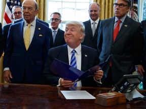 President Donald Trump, flanked by Commerce Secretary Wilbur Ross, left, and Energy Secretary Rick Perry, is seen in the Oval Office of the White House in Washington Friday, March 24, 2017, during the announcing of the approval of a permit to build the Keystone XL pipeline, clearing the way for the $8 billion project.