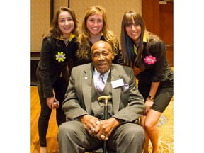 Apache volunteers  (L-R) Aoife Cunningham, Sarah Higdon and Lyza Chiarastella huddle with Stamps'  alumnus Ezzrett 'Sugarfoot' Anderson during the Apache Canada sponsored CUPS/Stampeders 20th Annual Kickoff Breakfast Friday morning  May 25, 2012 at the Hyatt Regency Hotel in Calgary.