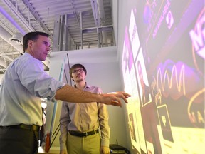 Minister of Finance Bill Morneau, left, touches an interactive display wall at Algonquin College before participating in a discussion on skills and innovation measures in the federal budget.