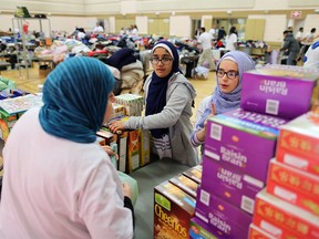 Hayat Amir, left, organizes food donations with twelve year-old volunteers Iqra Jamil and Kawthar Aroua at the Muslim Families Network Society Halal Food and Clothing Distribution event at the Marlborough Park Community Centre on Sunday March 19, 2017. Gavin Young/Postmedia Network