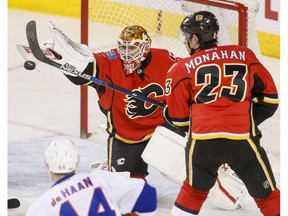 Calgary Flames goalie Brian Elliott swats at a puck near teammate Sean Monahan and Calvin de Haan of the New York Islanders in Calgary on Sunday, March 5, 2017. (Lyle Aspinall)