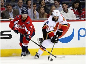 Karl Alzner #27 of the Washington Capitals and Deryk Engelland #29 of the Calgary Flames go after the puck in the third period at Verizon Center on March 21, 2017 in Washington, DC.