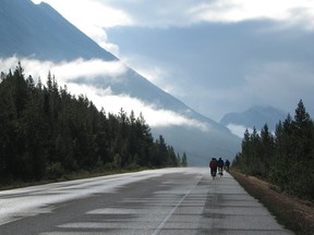 Cyclists ride into early morning sunlight after overnight showers on the Icefields Parkway.