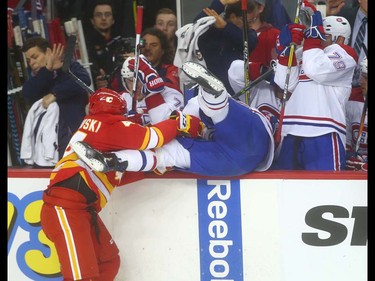 Flames Matt Bartkowski hits Canadiens Michael McCarron into the bench area during NHL action between the Montreal Canadiens and the Calgary Flames in Calgary, Alta. on Thursday March 9, 2017 at the Scotiabank Saddledome. Jim Wells/Postmedia