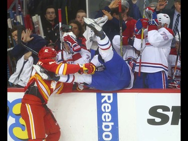 Flames Matt Bartkowski hits Canadiens Michael McCarron into the bench area during NHL action between the Montreal Canadiens and the Calgary Flames in Calgary, Alta. on Thursday March 9, 2017 at the Scotiabank Saddledome. Jim Wells/Postmedia