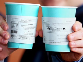 Dian Volschenk and Ben Wright pose with the coffee cups they have been handing out with their mini resumes posted on the Cup sleeve. Al Charest/Postmedia