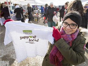 Deanna Reyes-Kinzer, who normally works with Matt and Sophie's Cakes, sells vendor-supporting T-shirts during a pop-up farmers market at Symons Valley Ranch in Calgary, Alta., on Saturday, March 4, 2017. A handful of vendors were back in business briefly, albeit outdoors, after a large fire decimated their facility a few metres away weeks earlier. Lyle Aspinall/Postmedia Network