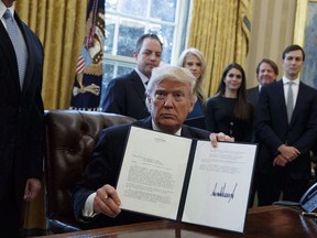 U.S. President Donald Trump shows his signature on an executive order on the Keystone XL pipeline, Tuesday, Jan. 24, 2017, in the Oval Office of the White House in Washington.