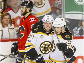 Matt Beleskey and Ryan Spooner of the Boston Bruins celebrate a third-period goal as Michael Frolik of the Calgary Flames skates by during NHL action in Calgary, Alta., on Wednesday, March 15, 2017. Boston won 5-2, snapping a 10-game Flames winning streak.