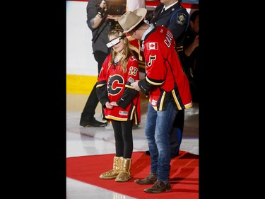 Legally blind Olivia Lettich, 11, wears special glasses while standing with anthem singer George Canyon before NHL action between the Calgary Flames and New York Islanders in Calgary, Alta., on Sunday, March 5, 2017. Lettich has battled eye cancer and is legally blind, but with these special glasses she was able to watch her very first Flames game. Lyle Aspinall/Postmedia Network