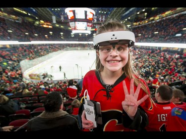 Legally blind Olivia Lettich, 11, wears an eSight unit during the second intermission of NHL action between the Calgary Flames and New York Islanders in Calgary, Alta., on Sunday, March 5, 2017. Lettich has battled eye cancer and is legally blind, but with these special glasses she was able to watch her very first Flames game. Lyle Aspinall/Postmedia Network