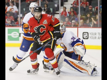 Troy Brouwer of the Calgary Flames fends off Travis Hamonic of the New York Islanders in front of goalie Jean-Francois Berube during NHL action in Calgary, Alta., on Sunday, March 5, 2017. The Flames won 5-2, marking their seventh straight win. Lyle Aspinall/Postmedia Network