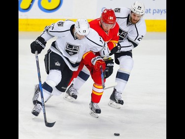 Calgary Flames forward  Curtis Lazar battle against Kyle Clifford and Derek Forbort  of the Los Angeles Kings in Calgary on March 19, 2017