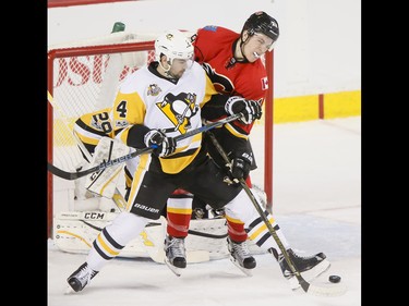 Matthew Tkachuk of the Calgary Flames fights for the puck with Justin Schultz of the Pittsburgh Penguins in front of goalie Marc-Andre Fleury during NHL action in Calgary, Alta., on Monday, March 13, 2017. The Flames were gunning for their 10th-straight win, which would set a new franchise record. Lyle Aspinall/Postmedia Network