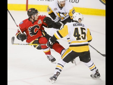 Sean Monahan of the Calgary Flames falls after reeling off a shot between Ian Cole and Josh Archibald of the Pittsburgh Penguins during NHL action in Calgary, Alta., on Monday, March 13, 2017. The Flames were gunning for their 10th-straight win, which would set a new franchise record. Lyle Aspinall/Postmedia Network