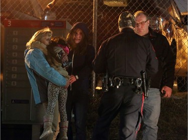 Members of the public, visibly upset, talk with a police officer beside A Trend Auto Service at 1818 35th St. S.E.