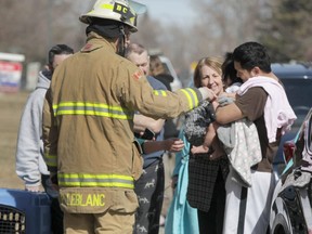 Calgary Fire Department Battalion Chief Paul LeBlanc greets a baby and a family displaced by a fire in their home on 23 St SE in Calgary, Alta on Saturday March 25, 2017. It was the second of three major building fires for CFD in less than 24 hours. They continue to investigate this fire, a blaze in Sundance on Friday night, and a fire at a strip mall on Macleod Tr S. Jim Wells/Postmedia