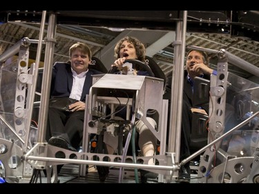 Chris Tucker (L) and Dave Vellutini ride shotgun as Susan Bennett takes a spin in a Ford driving simulator during the 18th annual Vehicles and Violins gala at the BMO Centre in Calgary, Alta., on Tuesday, March 14, 2017. Vehicles and Violins is a black-tie preview of the 2017 Calgary International Auto and Truck Show, featuring Calgary Philharmonic Orchestra musicians. Lyle Aspinall/Postmedia Network