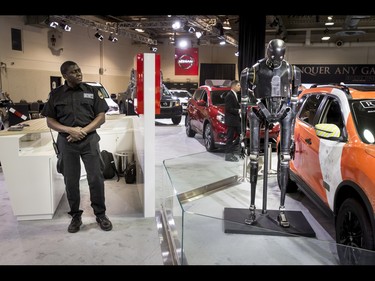 A security guard eyes a K-2SO droid from the Star Wars movie Rogue One during the 18th annual Vehicles and Violins gala at the BMO Centre in Calgary, Alta., on Tuesday, March 14, 2017. Vehicles and Violins is a black-tie preview of the 2017 Calgary International Auto and Truck Show, featuring Calgary Philharmonic Orchestra musicians. Lyle Aspinall/Postmedia Network