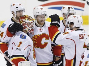 Calgary Flames goalie Brian Elliott (1) is congratulated by defenceman Dougie Hamilton (27) and other teammates for a shutout win against the Winnipeg Jets, in Winnipeg on Saturday, March 11, 2017.