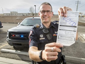 Acting Sgt. David DenTandt holds a voided traffic ticket outside of the Calgary Police Service's traffic office in Calgary, Alta., on Saturday, April 1, 2017. CPS is doing a short pilot project to dole out void tickets as warnings for minor traffic offences; if successful, it could become a more regular occurrence. Lyle Aspinall/Postmedia Network