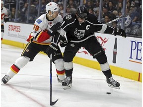 Calgary Flames right winger Alex Chiasson (39) and Los Angeles Kings center Anze Kopitar (11) tangle, earning Kopitar a holding penalty during the first period of an NHL hockey game in Los Angeles Thursday, April 6, 2017.