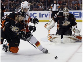 Anaheim Ducks center Antoine Vermette, left, vies for the puck with Calgary Flames right wing Alex Chiasson, center, on a deflection by Ducks goalie John Gibson, right, in Anaheim, Calif., Tuesday, April 4, 2017.