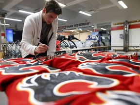 Sean Monahan signs jerseys in the Flames workout room.