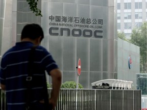 A man stands outside the headquarters building of China National Offshore Oil Corporation (CNOOC) in Beijing on July 29, 2016. China's main offshore oil and gas producer CNOOC will lose more than 1 billion USD in the first half of this year because of low oil prices, it told shareholders in a profit warning on July 29. /