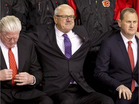 Ken King, president and CEO of the Calgary Flames, puts his arms around Brian Burke (L), president of hockey operations, and GM Brad Treliving while setting up for a team photo at the Scotiabank Saddledome in Calgary, Alta., on Tuesday, March 28, 2017.