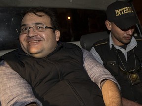 Mexico's former Veracruz state Gov. Javier Duarte, left, is escorted by an agent of the local Interpol office inside a police car as they arrive at Guatemala City, early Sunday, April 16, 2017. Duarte, who is accused of running a ring that allegedly pilfered from state coffers, has been detained in Guatemala after six months as a fugitive and a high-profile symbol of government corruption. (AP Photo/Moises Castillo)