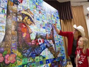 Karen Bishop and Allison Lento, 6, look for the piece that she painted on the Woodlands School Canada 150 Mosaic unveiled in Calgary, Alta., on April 6, 2017.