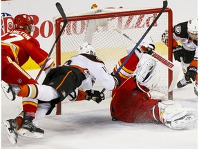 Calgary Flames goalie Brian Elliott takes a spill between Corey Perry and Andrew Cogliano of the Anaheim Ducks near Flames teammate Dougie Hamilton in Calgary on Sunday, April 2, 2017. (Lyle Aspinall)