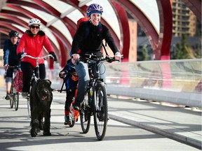 Shelley Cyre and her son Wyatt chug along the Peace Bridge with their dog Midas while family friend Marla Heim follows behind in Calgary, Alta., on April 17, 2017. The Cyre family will be taking some time to see Canada from the road as they take on a four month tour to celebrate Canada 150. Ryan McLeod/Postmedia Network