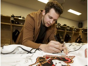 Tyler Mrkonjic signs autographs during locker-room clean-out day for the Calgary Hitmen at the Scotiabank Saddledome in Calgary, Alta., on Saturday, April 1, 2017. The Hitmen were swept out in the first round of WHL playoffs by the Regina Pats.