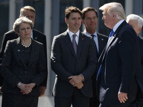 U.S. President Donald Trump walks past Prime Minister Justin Trudeau at the NATO meeting in Brussels on Thursday.